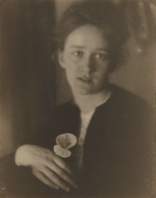 Portrait of a woman holding flower, 1900