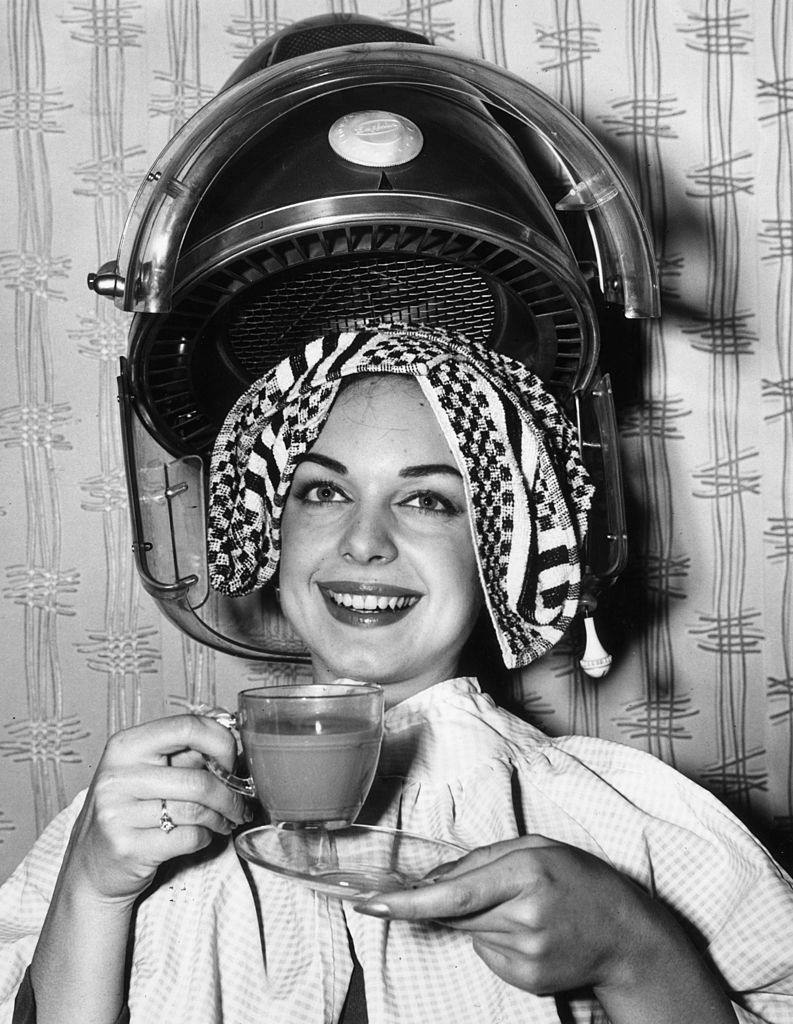 Louise Crous, Miss South Africa 1963, drinks a cup of coffee as she gets her hair done in preparation for the Miss World beauty pageant, London, 1963