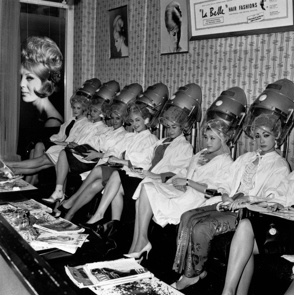 A group of Miss World contestants line up under the hairdryers at La Belle hairdressing salon in Aldwych, London, 1963