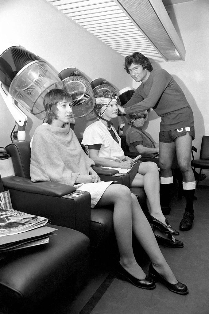 Vidal Sassoon dressed in Chelsea's Football strip seen in the women's hairdressing salon attending to some clients, 1972