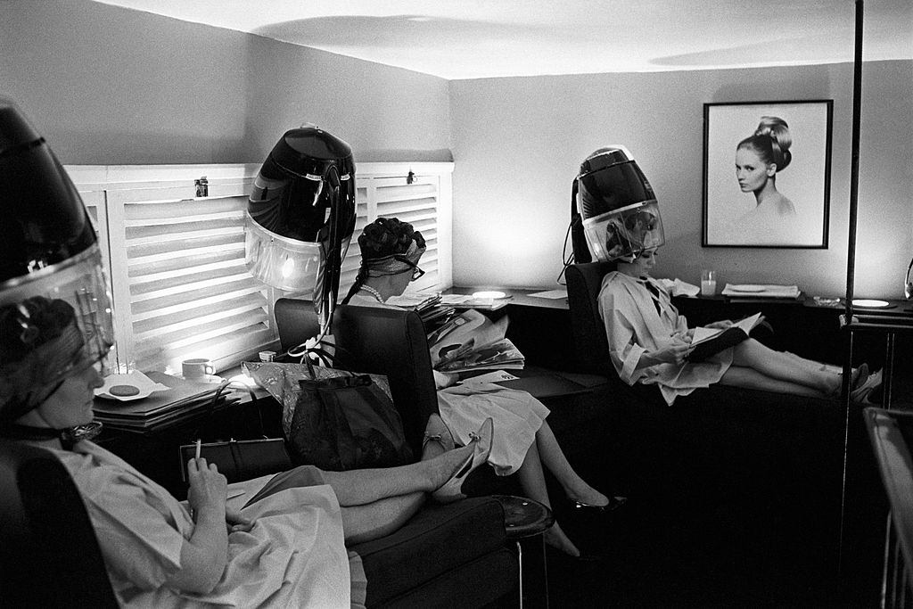 At the hairdresser's, some British women reading magazines under the hair dryer, London, 1960s.
