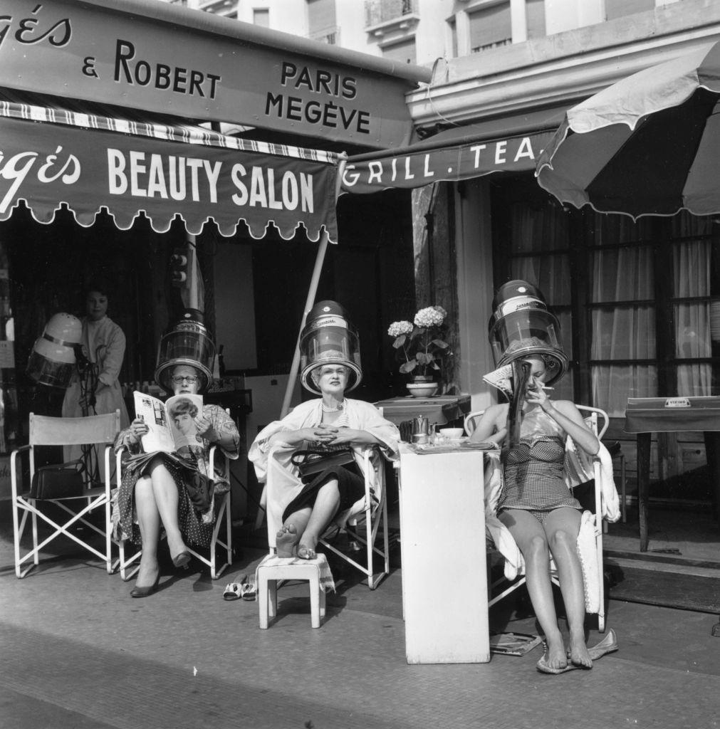 Visitors sit beneath the dryers at an open air hairdressing salon overlooking the Mediterranean Sea during the Cannes Film Festival, 1958