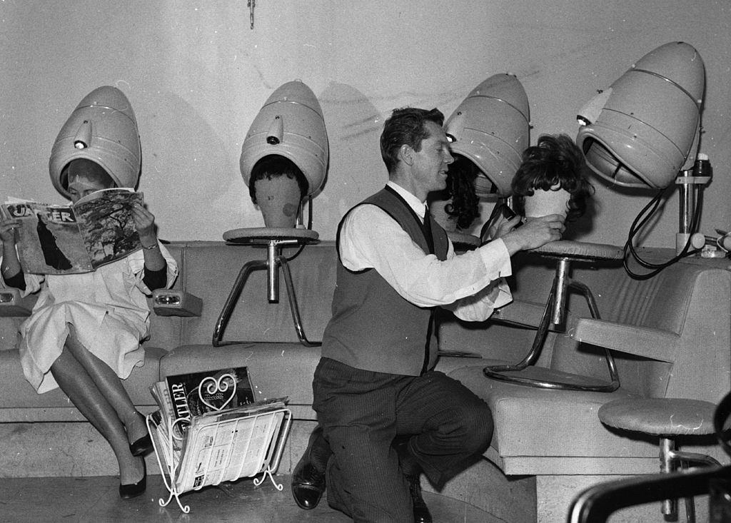 A hairdresser drying wigs under the salon's hairdryers.