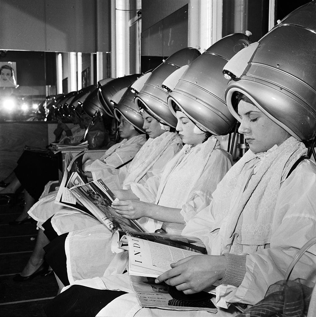 Women relax underneath the hairdryers in a self-service hairdressing salon, 1956