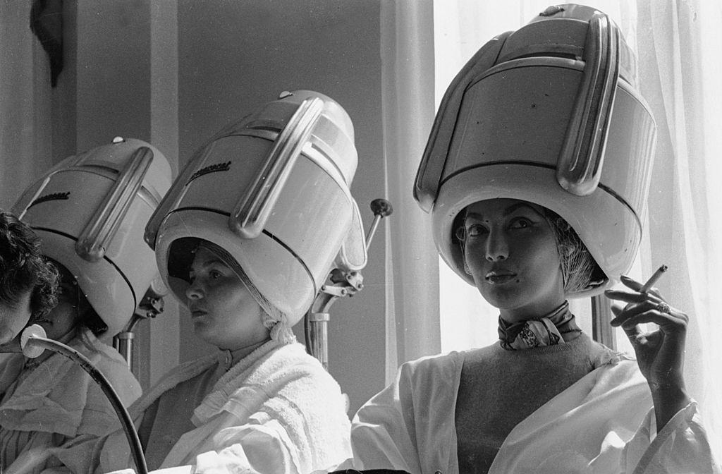 Spanish fashion model, Teresita Montes, sister of the film star Maria Montes, sitting under a Parisian beauty salon's hairdryer smoking a cigarette, 1955