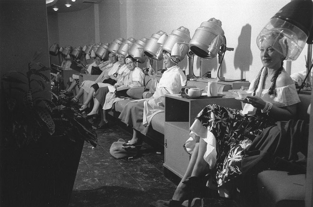 Frances Day and a group of women enjoying a cup of tea whilst sitting under the hairdryers at the Martin Douglas and Rene hair salon.