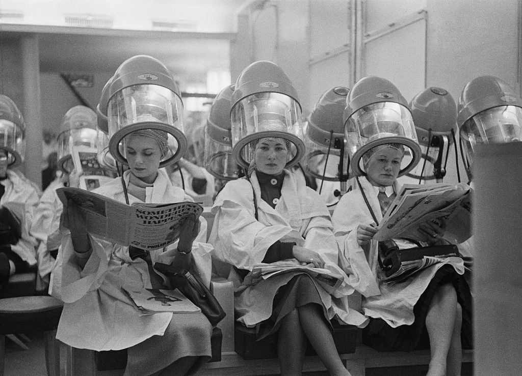 A row of British women sitting under hairdryers in a Paris salon, 1954