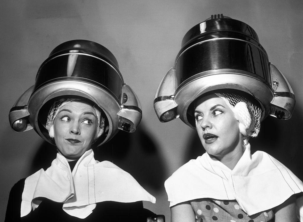 Two women gossping under Hairdresser hair dryer, 1950s