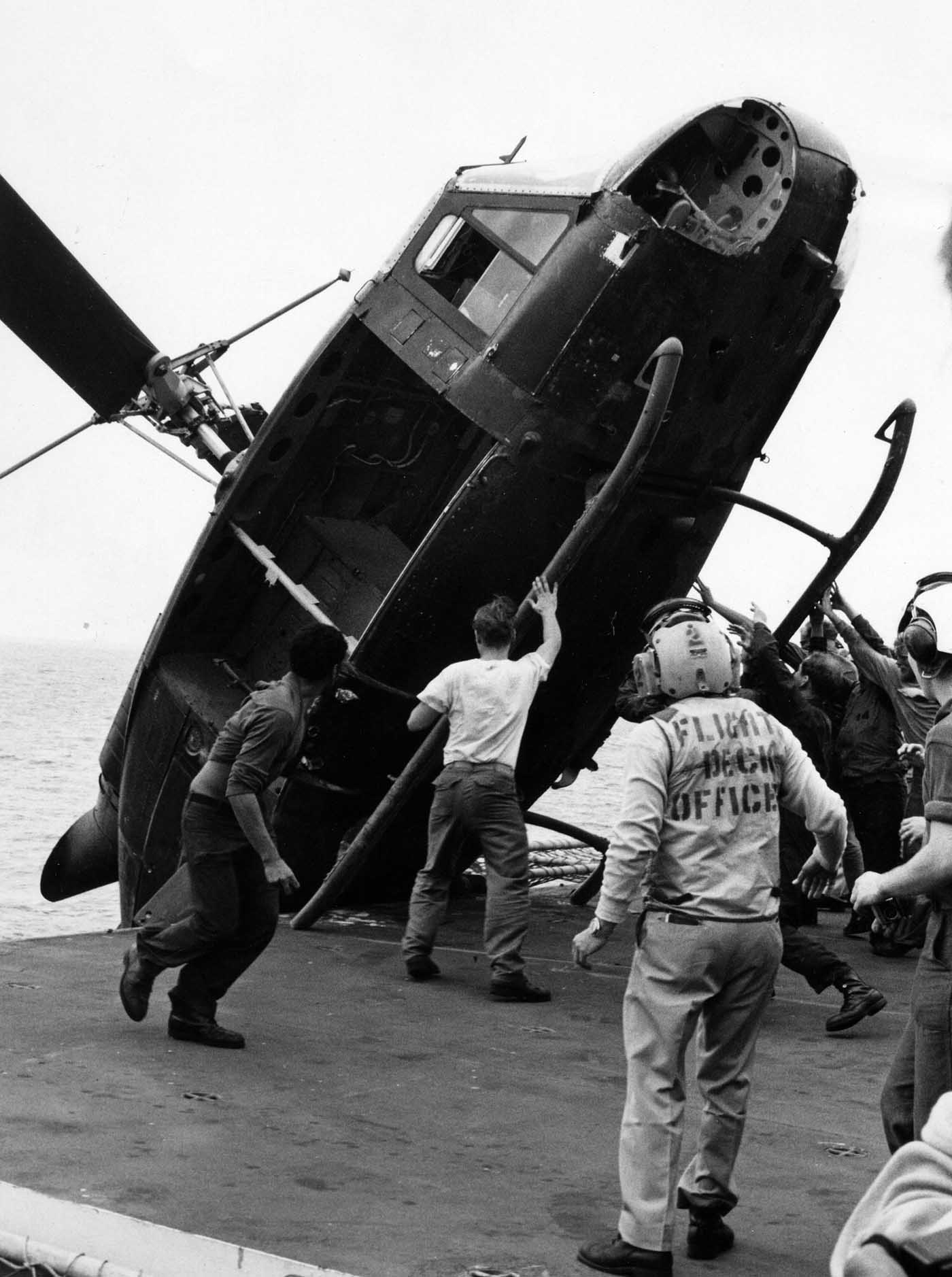 A South Vietnamese helicopter is pushed overboard from USS Okinawa to clear deck space for more incoming helicopters.