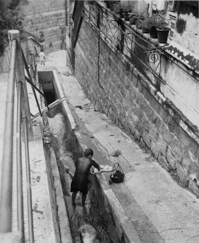 Woman doing laundry in gutter, Hong Kong, August 31, 1945