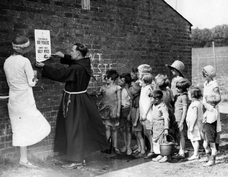 Hop pickers' children watch as a Franciscan friar puts up a notice of a church service, 1933.