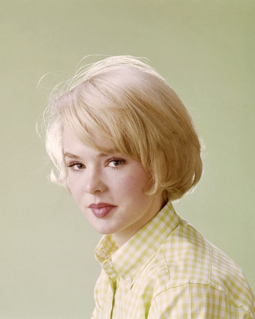 Joey Heatherton, wearing a yellow and white check blouse in a studio portrait, against a yellow background, circa 1965.