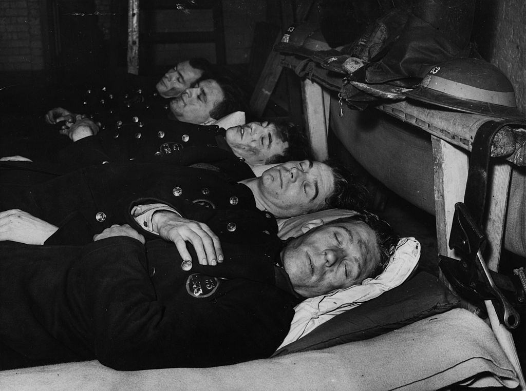 After 12 hours fire fighting during the London blitz firemen enjoy a sleep but keep on their uniform.