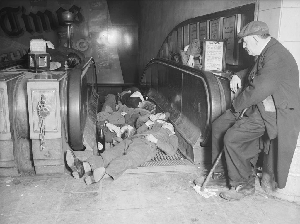 A group of men sleeping on an escalator as they shelter from an air raid, in a London Underground Station during the Blitz, 1940.