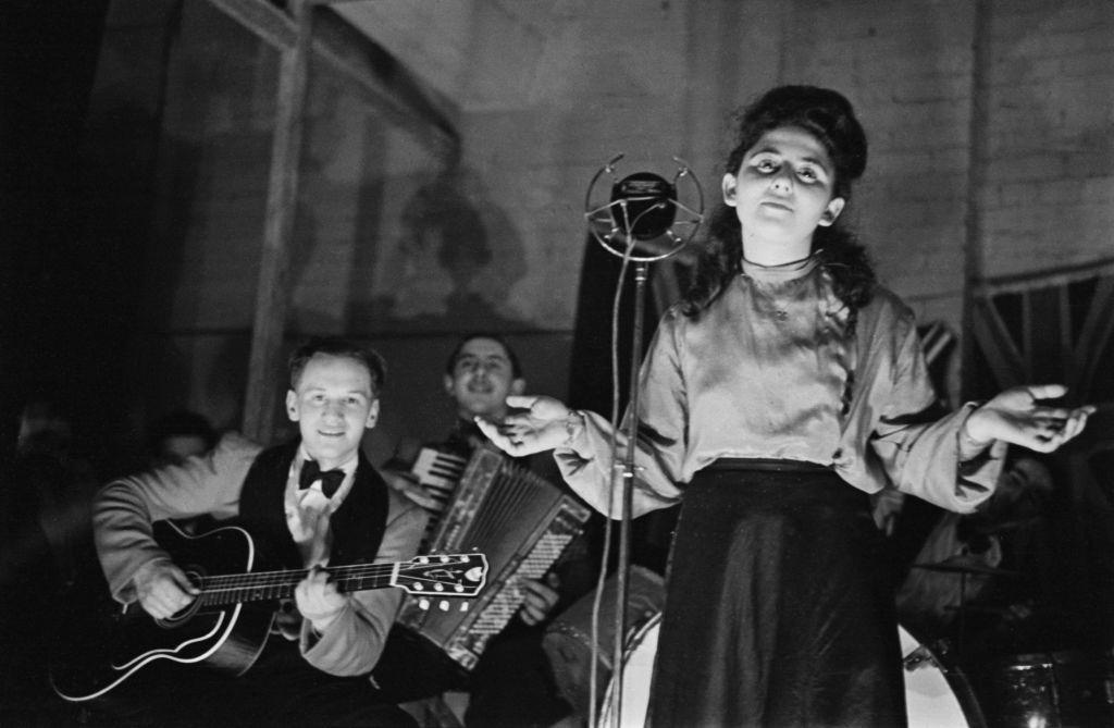 Shop worker Sadie Davis entertains her fellow employees with a song at the Dickens & Jones bomb shelter in the basement of the department store in Regent Street, London during the Blitz in World War II in March 1941.