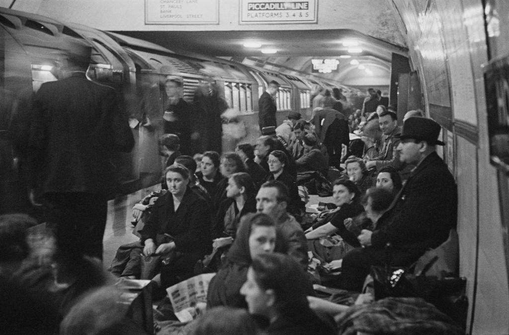 Wartime view as a train arrives of Londoners seeking shelter and waiting to bed down on the platform at Holborn underground station.