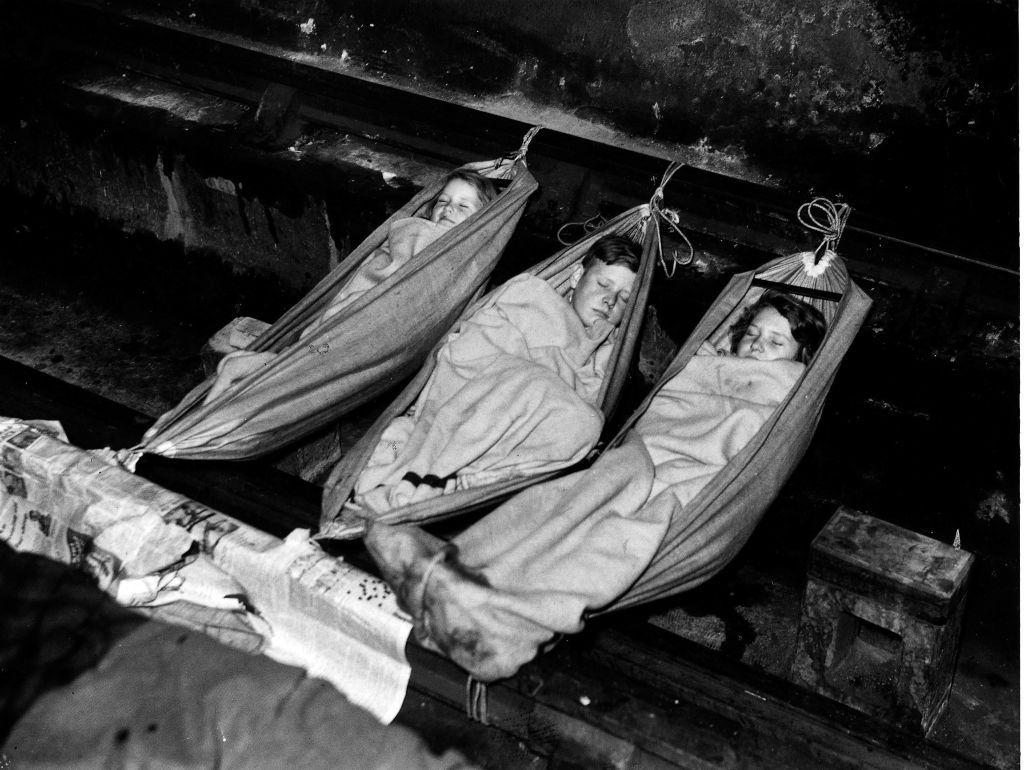 Three children sleeping in hammocks in a London shelter during The Blitz, 1940