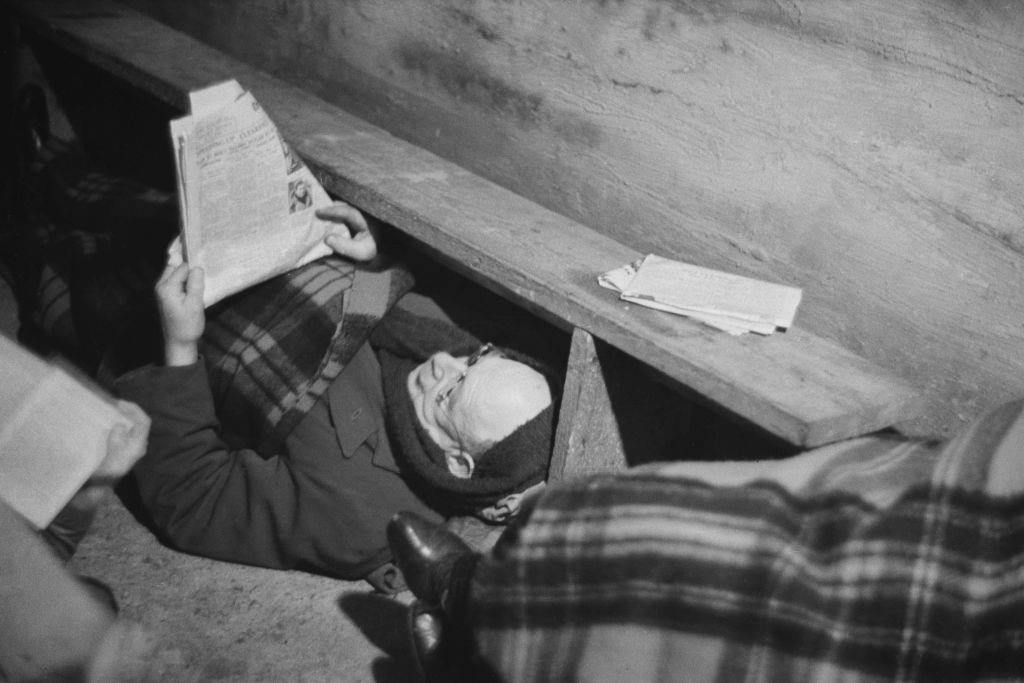 A man reading a newspaper in an air raid shelter during the Blitz, London, October 1940.