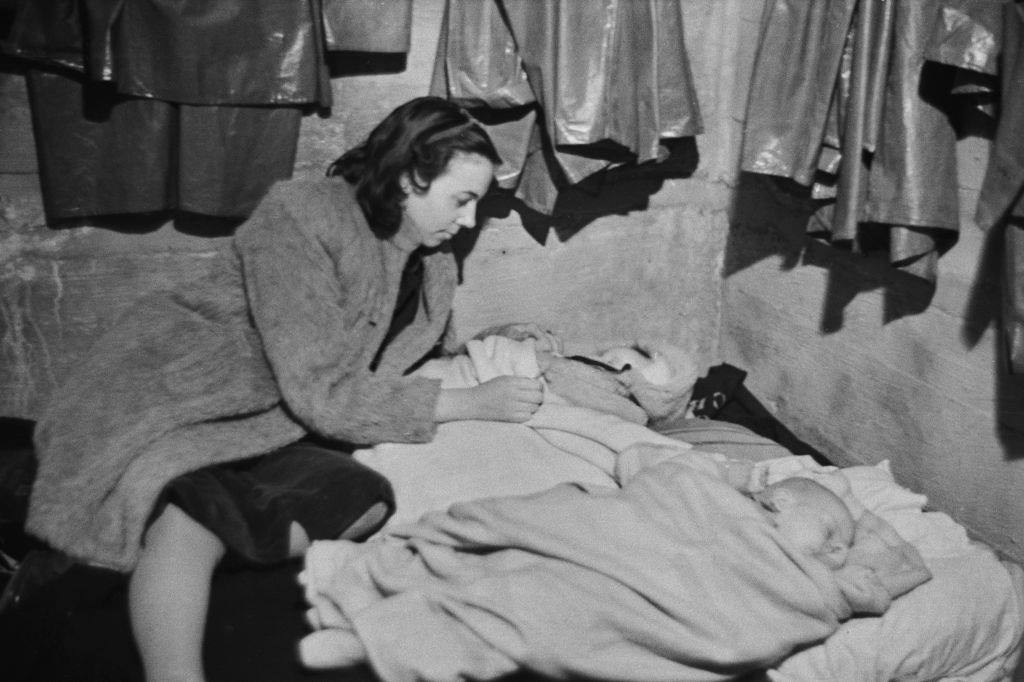 A woman tending to two babies in an air raid shelter during the Blitz, London, October 1940.