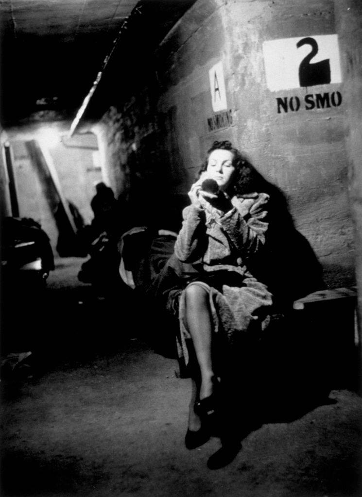 A woman applies make-up while waiting in a shelter during the Blitz, London, October 1940.