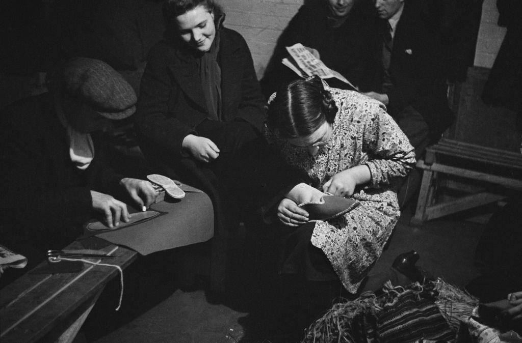 Londoners making slippers in a craft lesson given by London County Council (LCC) teachers at an air raid shelter in Bermondsey, London during the Blitz, March 1941.