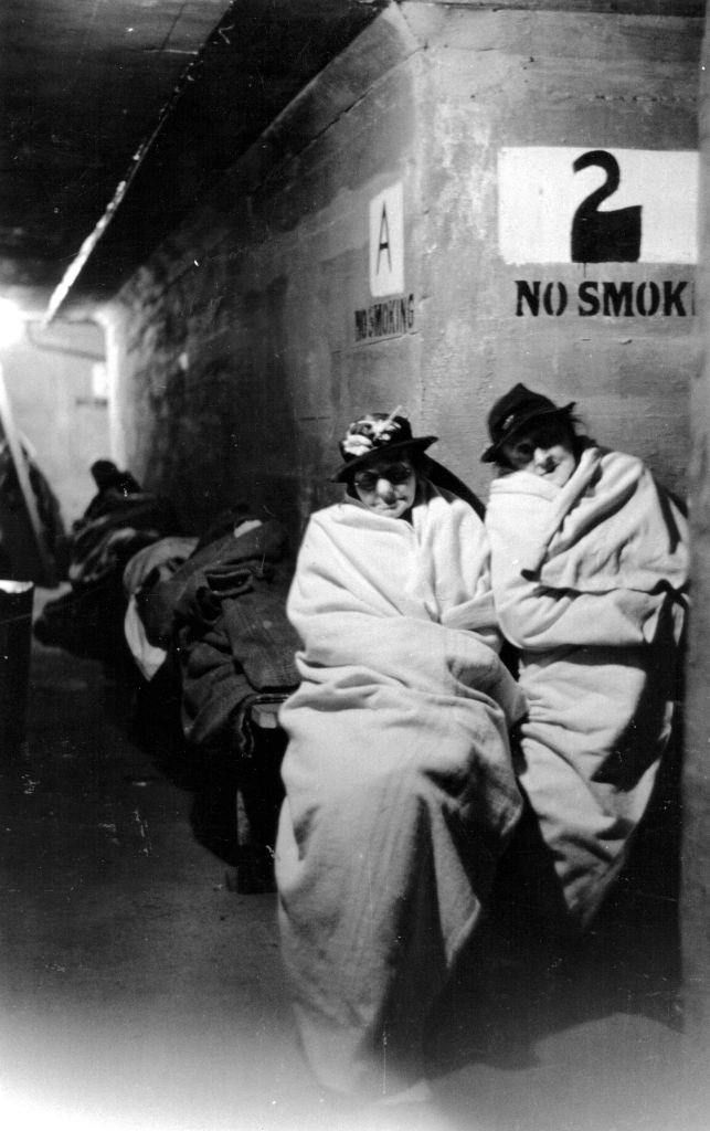 Two women wrapped up in blankets in an air raid shelter during the Blitz, London, October 1940.