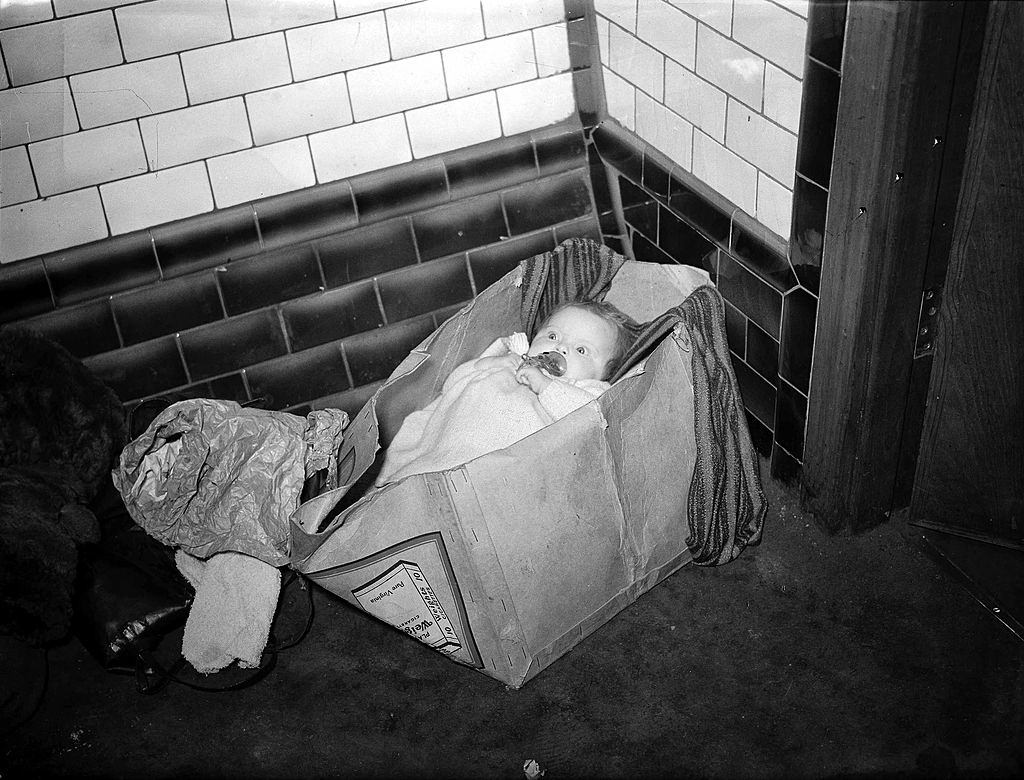 A baby tucked up in a packing case shelters from German daylight bombing deep in a corner of the Piccadilly Underground station.