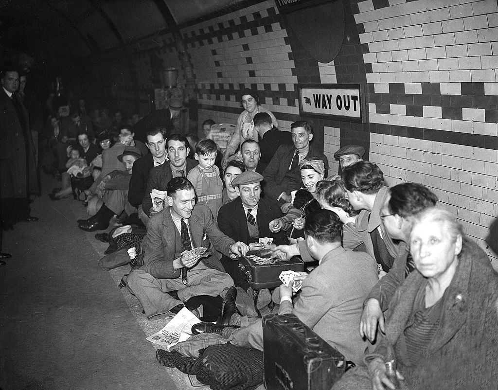 Members of the public huddle together in a London underground station, possibly the Bakerloo line platform at Piccadilly Circus, to avoid German bombs during the Blitz.