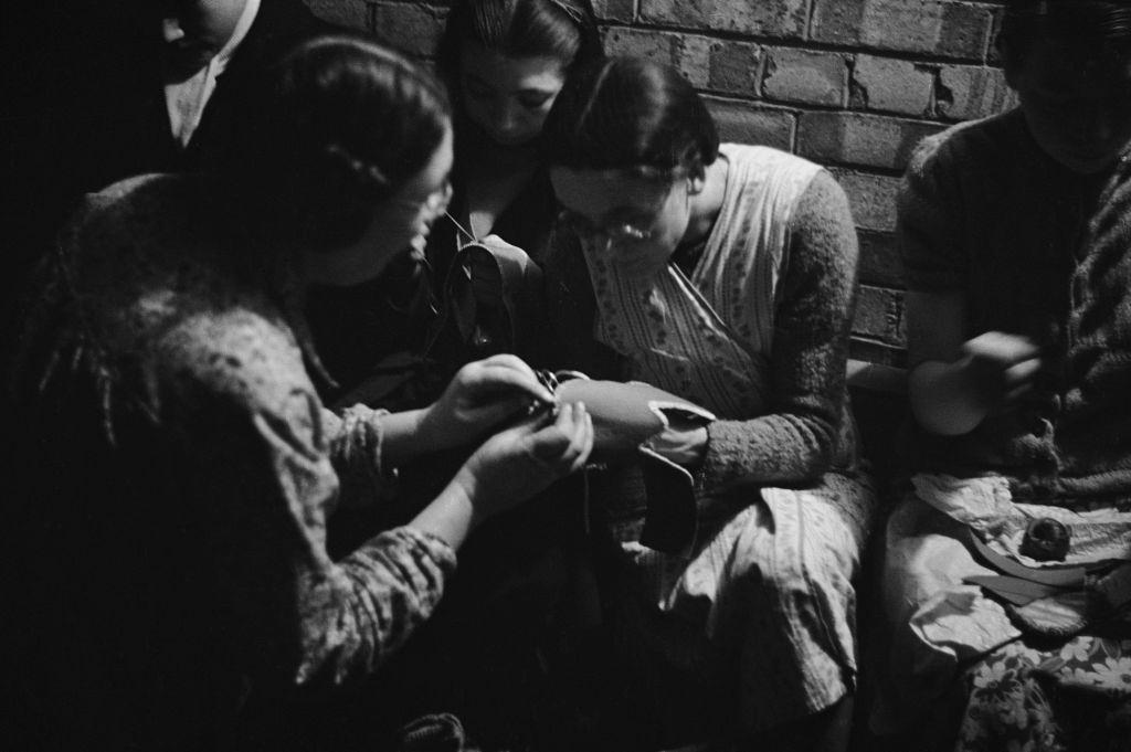 Londoners making slippers in a craft lesson given by London County Council (LCC) teachers at an air raid shelter in Bermondsey, London during the Blitz, March 1941.