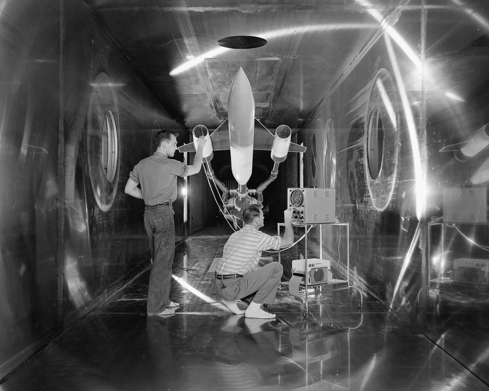 Engineers make a check of a model of a supersonic aircraft before a test run in the 10 x 10-foot Supersonic Wind Tunnel test section, 1957.