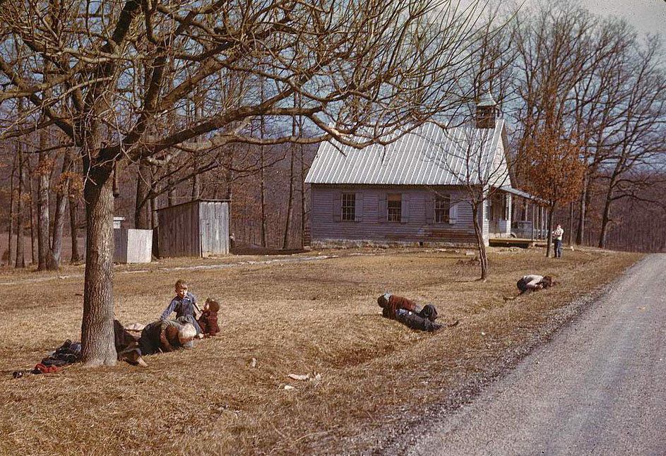 Children playing by road near school house, Kansas, 1950s