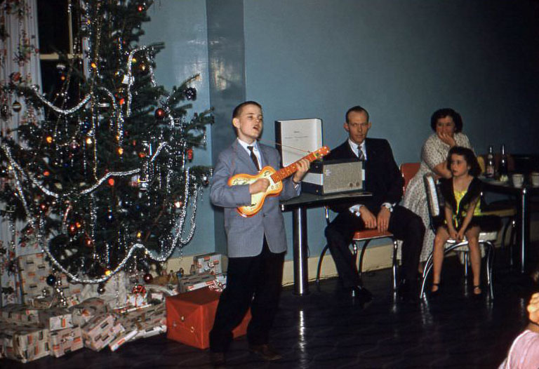 Boy singing and playing guitar at Christmas, 1950s