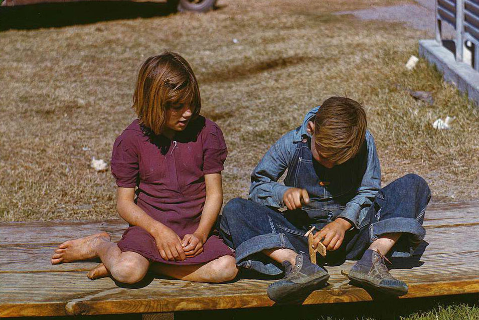 Boy building a model airplane as girl watches, FSA camp, Robstown, Texas, 1950s