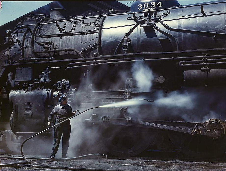 Mrs. Viola Sievers, one of the wipers at the roundhouse giving a giant "H" class locomotive a bath of live steam, Clinton, Iowa, 1950s