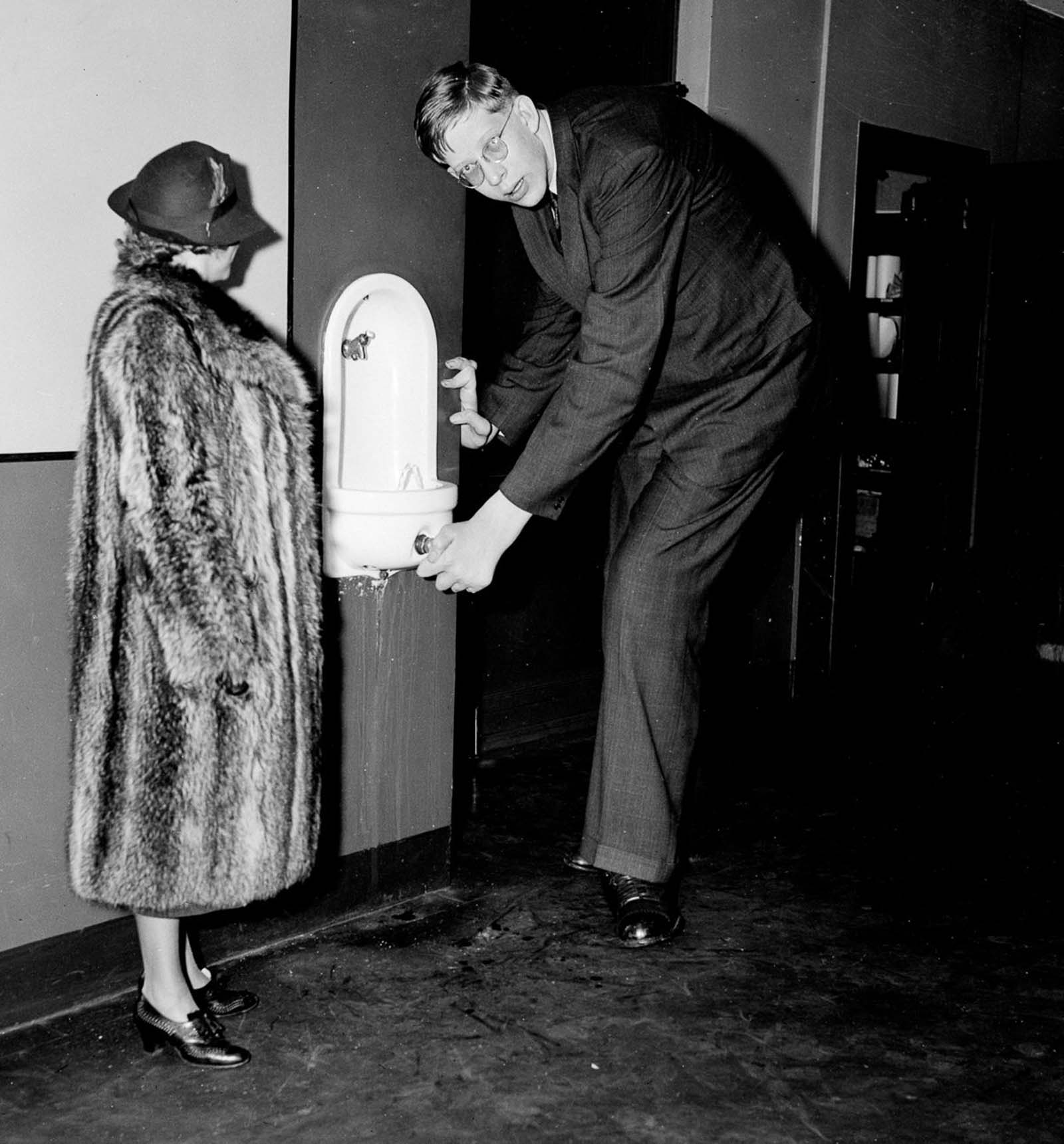 Wadlow stoops for a drink during a visit to the Daily News offices in New York, 1937.