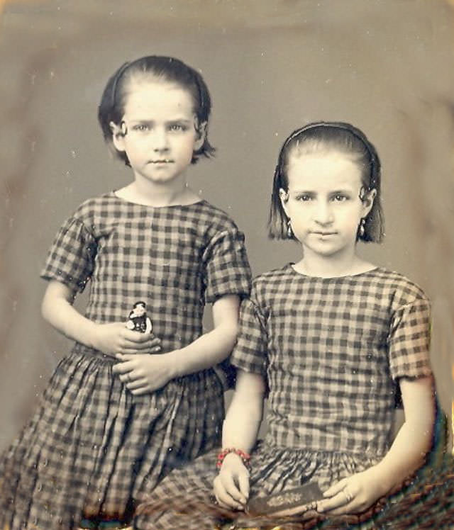 Sisters in matching dresses with book and doll