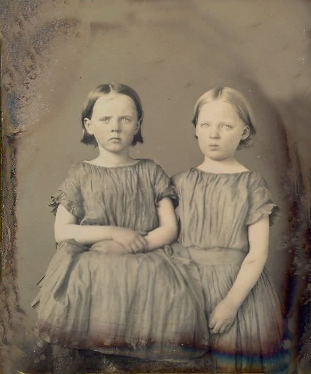 Two rural American children. Home made dresses and haircuts. Their hands appear dirty but are actually tan lines from working outside