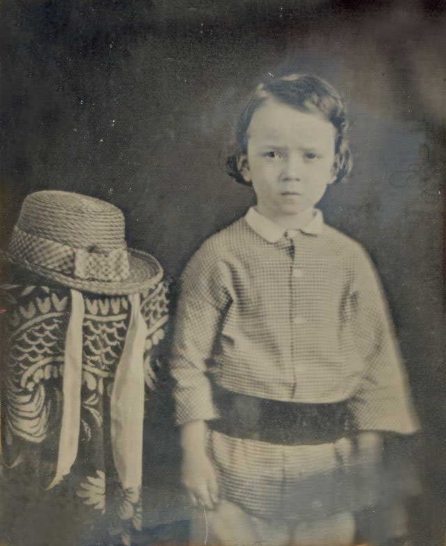 Young boy posed by a hat