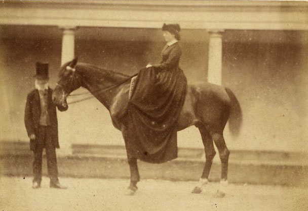 Man standing with woman on horse back