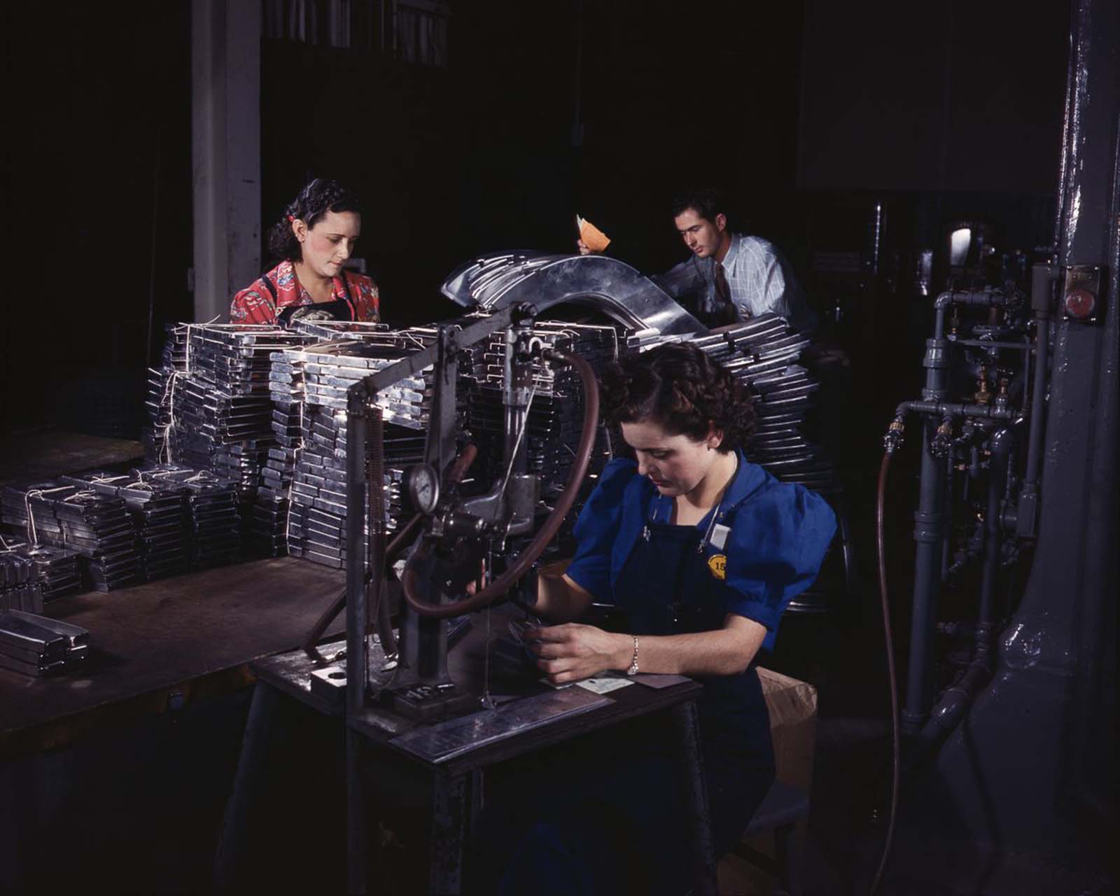 Workers feed sections of sheet metal through a pneumatic numbering machine at the North American Aviation plant in Inglewood, California, 1942.