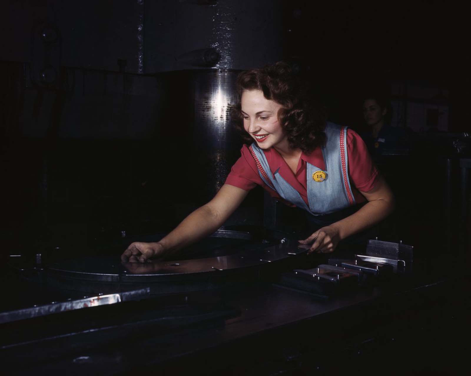 A North American Aviation employee places metal parts on masonite before sliding them under a hydraulic press at the plant in Inglewood, California, 1942.