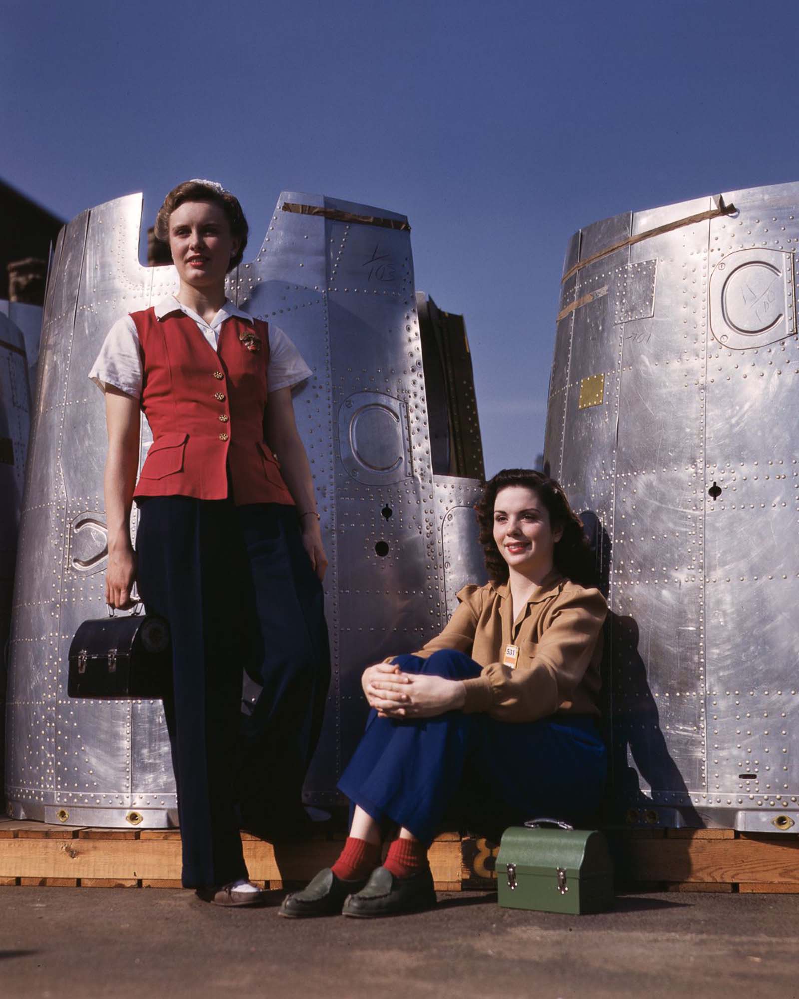 Two assembly workers take a lunch break next to heavy bomber nacelle parts at the Douglas Aircraft Company plant in Long Beach, California, 1942.