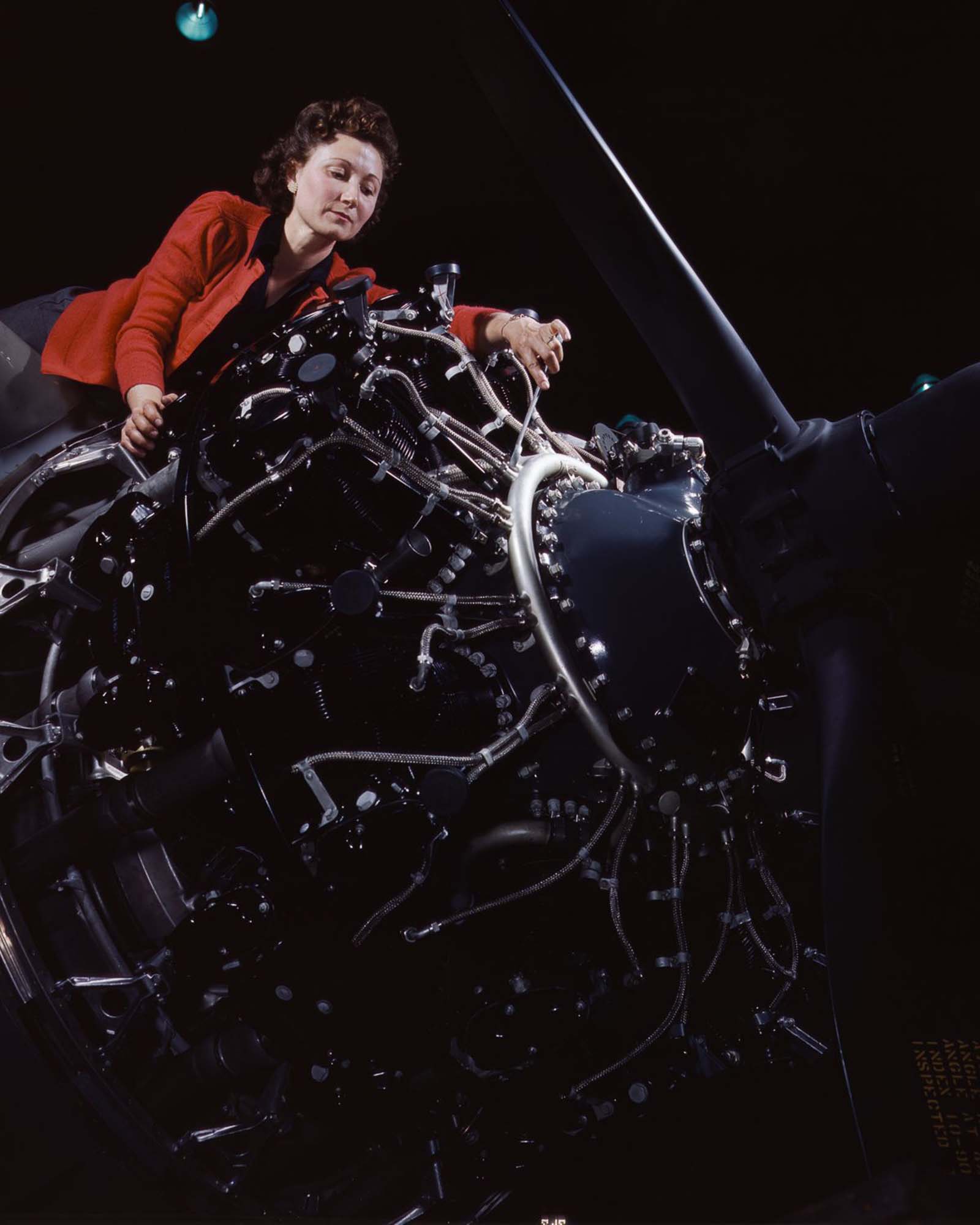 A worker makes adjustments to an airplane motor at the Douglas Aircraft Company plant in Long Beach, California, 1942.