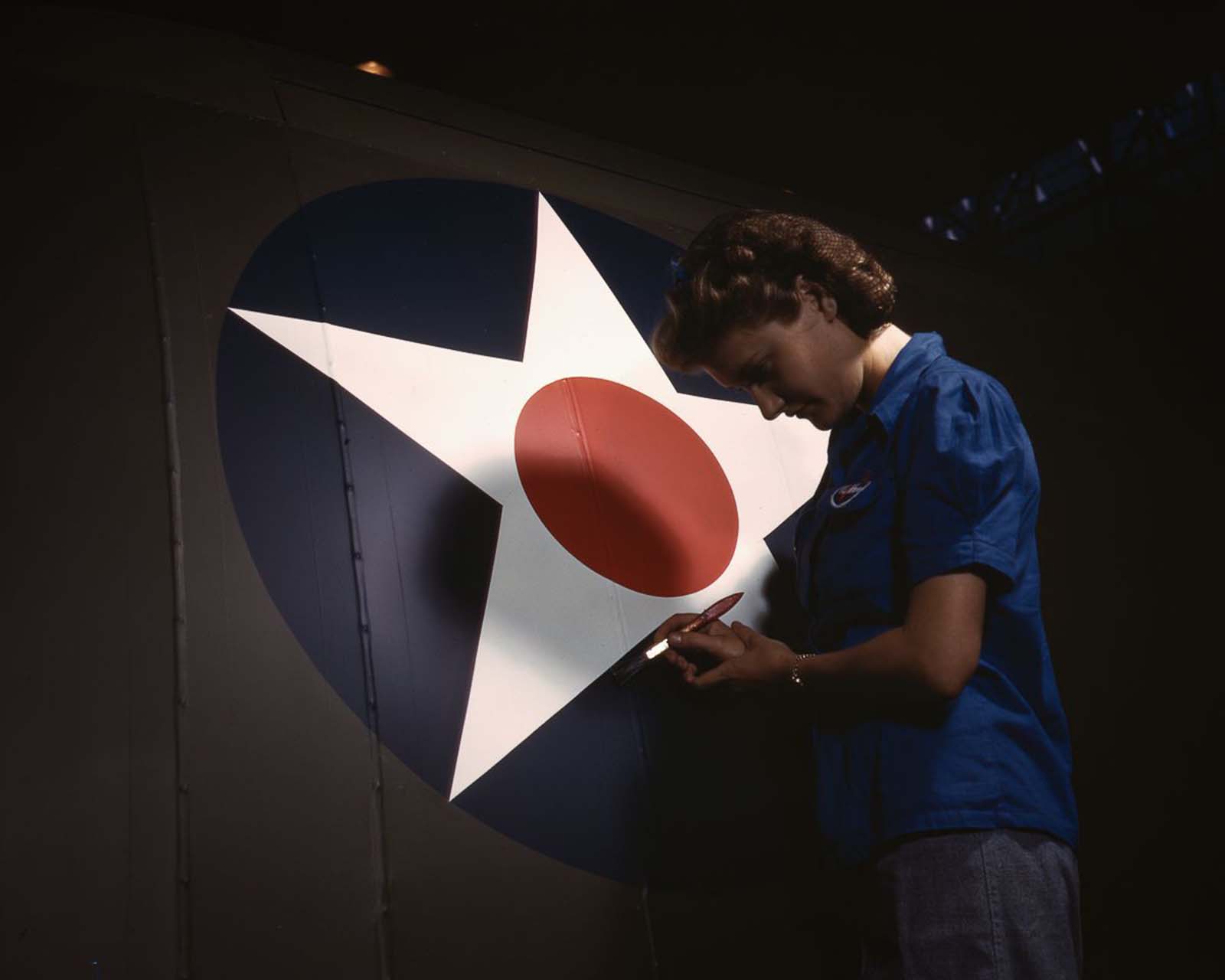 A Vultee Aircraft employee touches up the U.S. Army Air Forces insignia on the fuselage of a “Vengeance” dive bomber at the plant in Nashville, Tennessee, 1943.