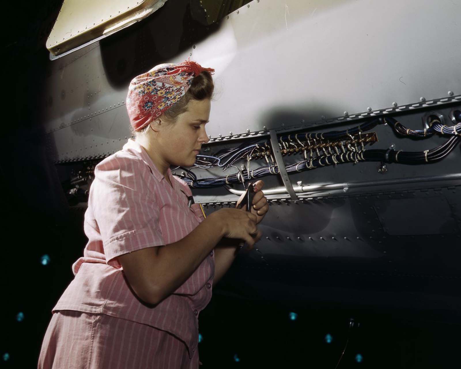 A Douglas Aircraft Company employee does delicate electrical work on a plane at the plant in Long Beach, California, 1942.