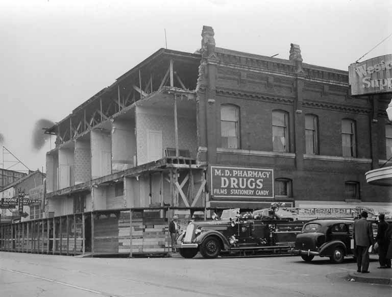 Fire engine in front of damaged building with M. D. Pharmacy, Olympia, April 1949
