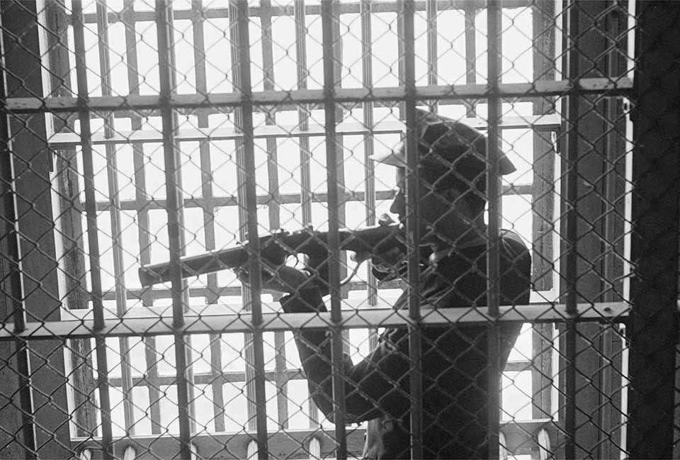 Guard in D-Block Gun Gallery - A correctional officer poses with his weapon in the D-Block gun gallery.