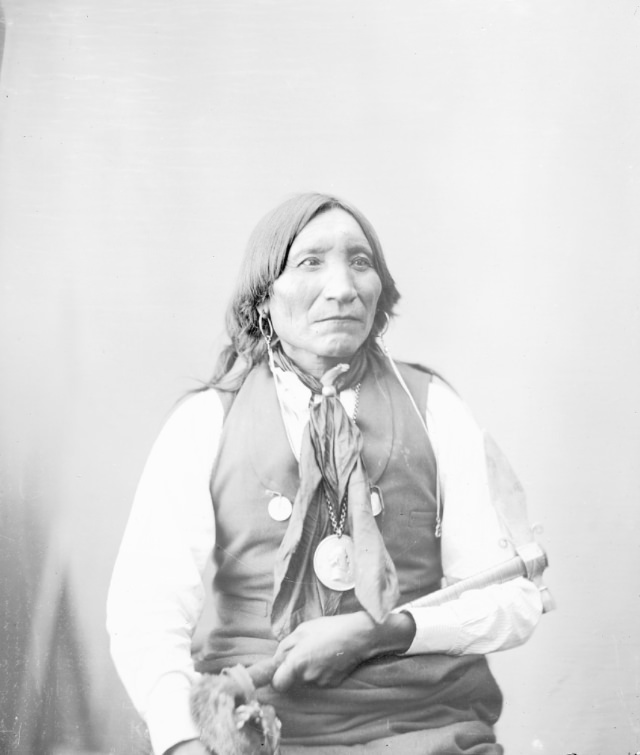 Guipago (Lone Wolf) wearing peace medal and holding pipe-tomahawk.