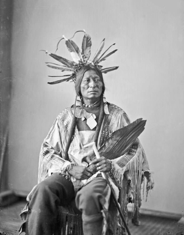 (Front) of Hatona or He-Otal (Many Horns) wearing headdress and holding pipe and feather fan.