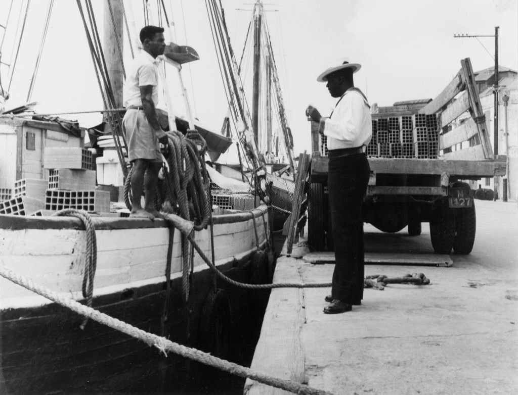 A ketch (twin-masted sail boat) sits at anchor in the Careenage, Bridgetown, 1965